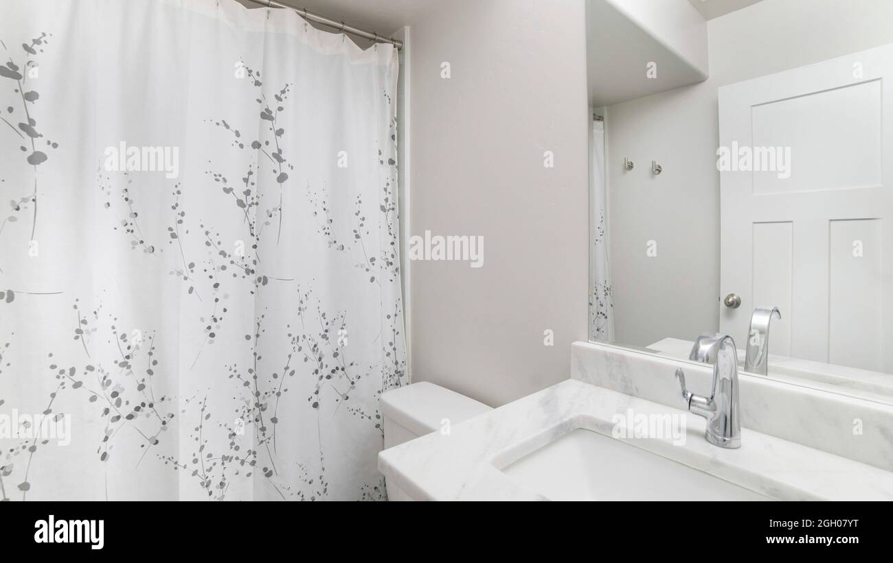 Pano interno di un bagno con lavandino bianco piano in marmo e specchio Foto Stock