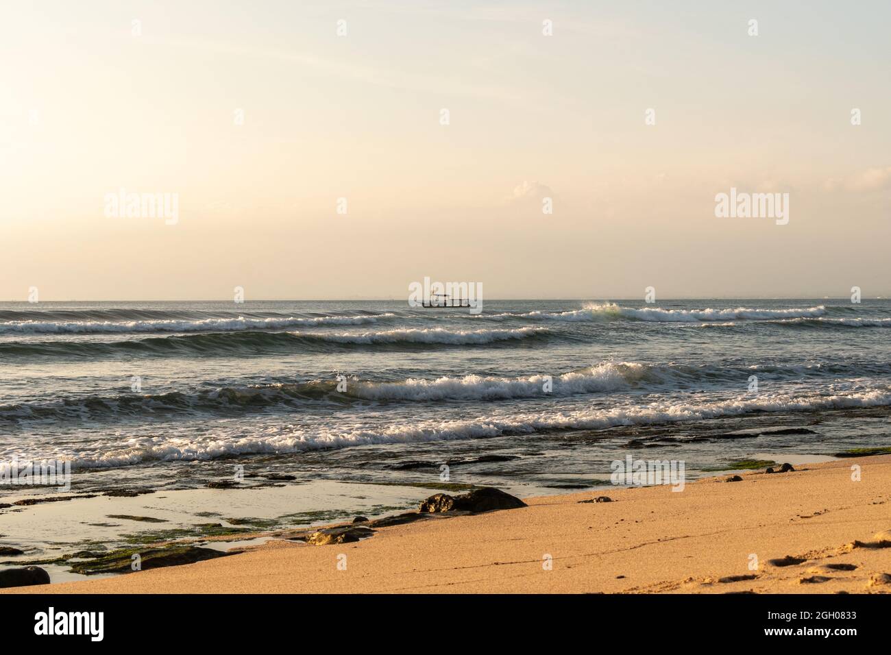 vista dalla spiaggia a una tradizionale barca da pesca tra le onde Foto Stock