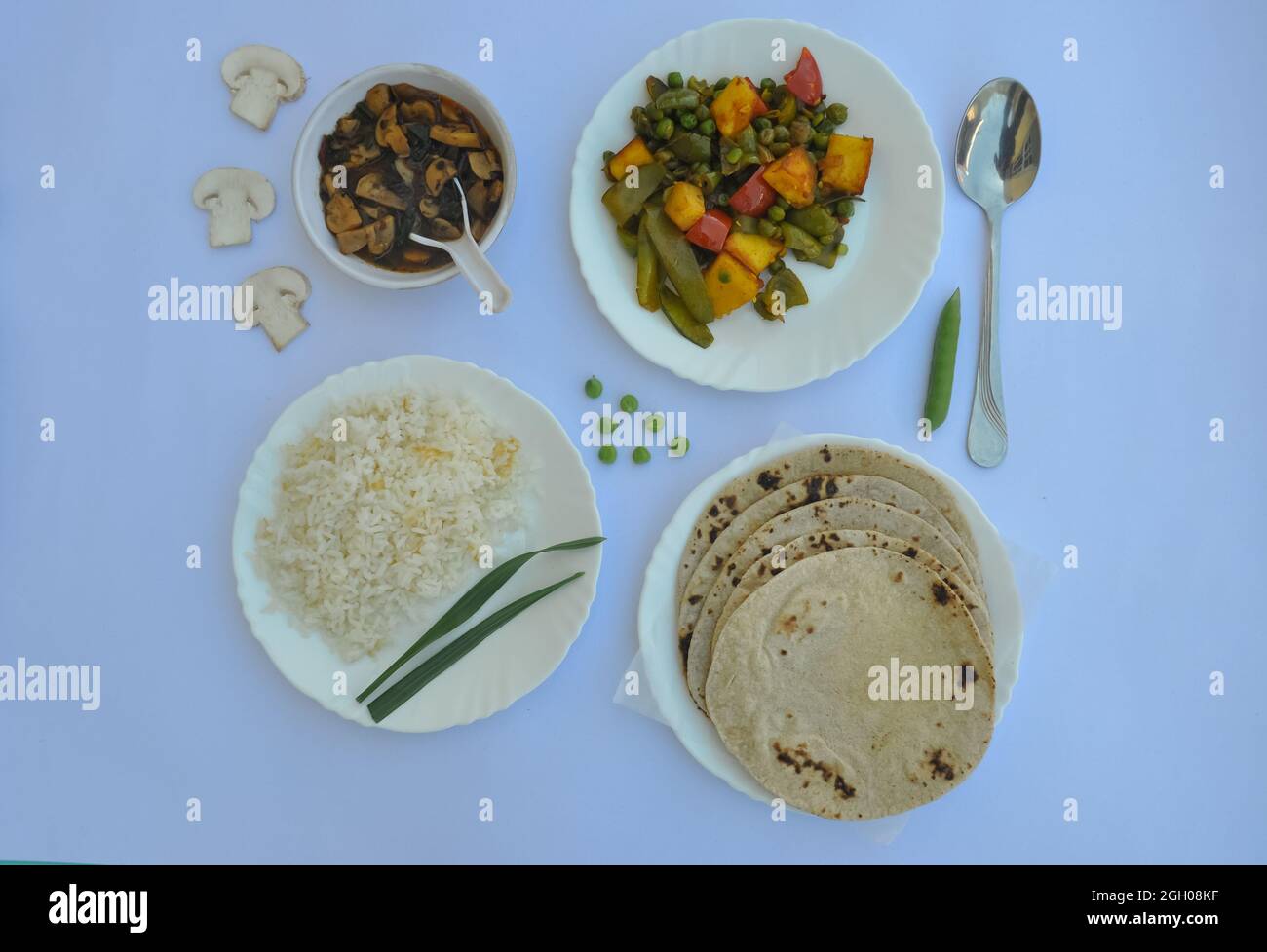 Vista dall'alto di veg paneer matar, zuppa di mashroom, roti (chapati) e riso (cibo indiano) isolato su sfondo bianco Foto Stock