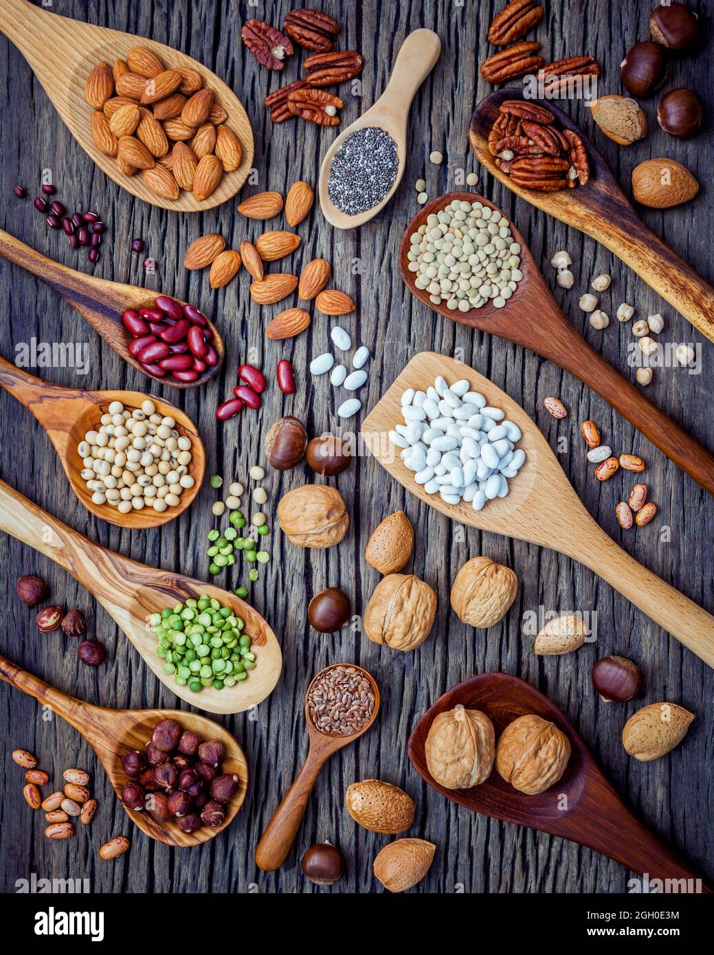 Legumi vari e diversi tipi di nutshells in cucchiai. I kernel di noci, nocciole, mandorle ,brown pinto ,i fagioli di soia ,semi di lino ,chia ,cece ,ri Foto Stock