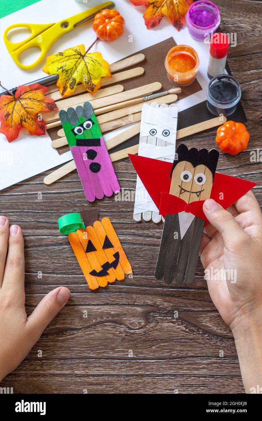Il bambino sta tenendo Halloween fantasma e vampiro giocattolo cuccioli di fantasticini su tavolo di legno. Fatto a mano. Progetto di creatività per bambini, artigianato, artigianato f Foto Stock