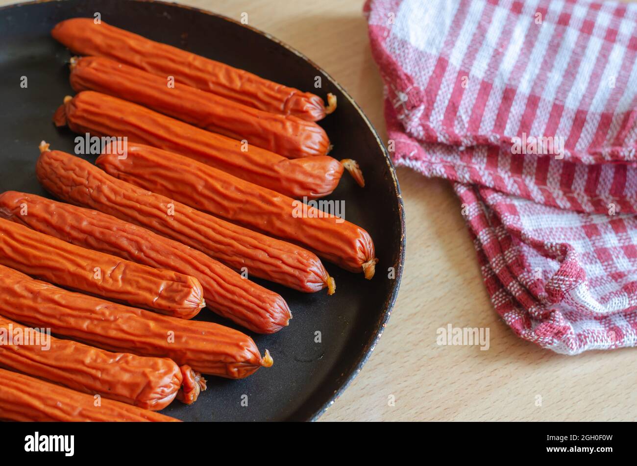 Una padella di salsicce da caccia su un tavolo beige. Una porzione di Ready-t Foto Stock