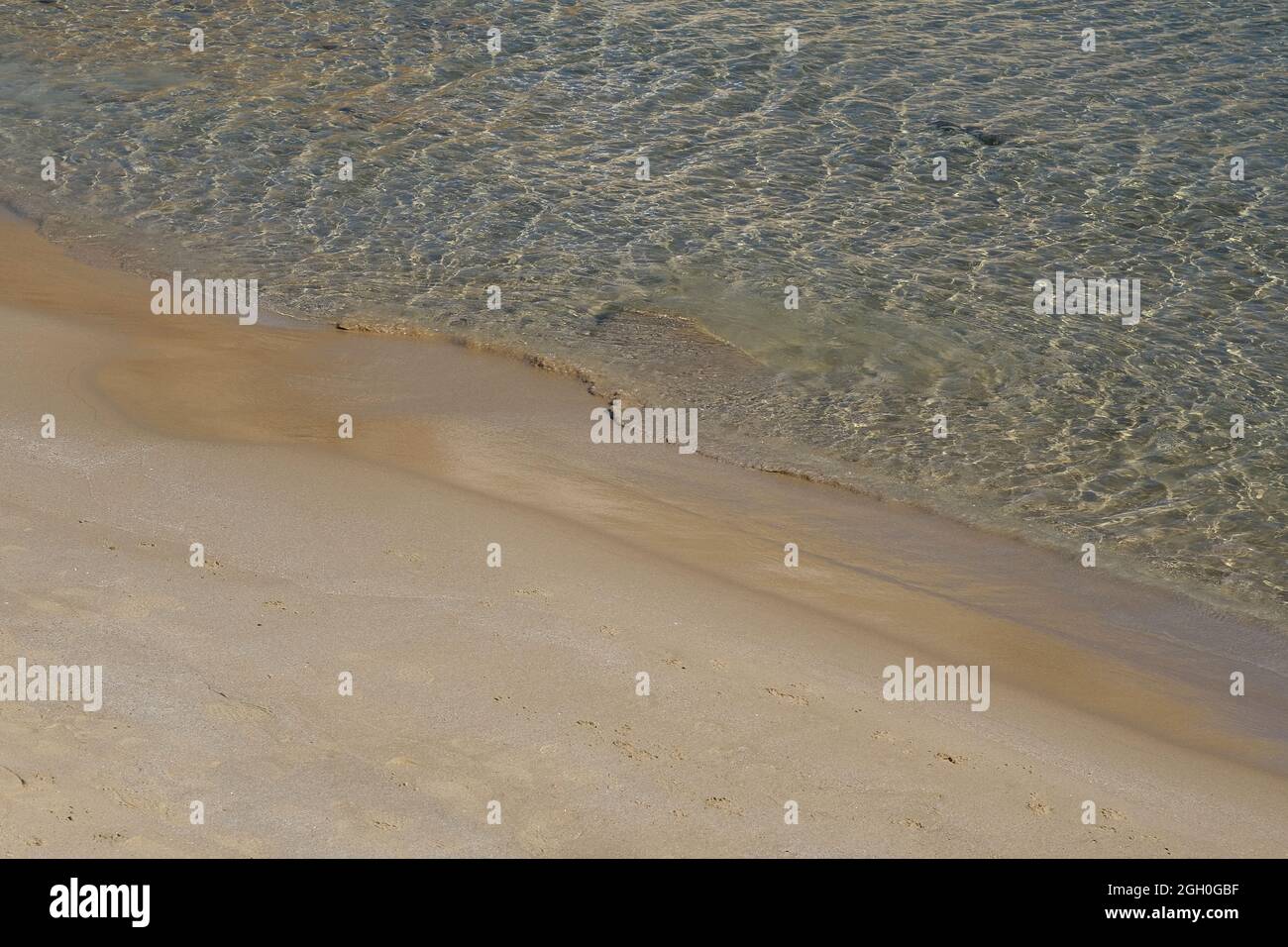 Primo piano di una bella spiaggia di sabbia con acque limpide attraverso il mare in iOS Grecia Foto Stock