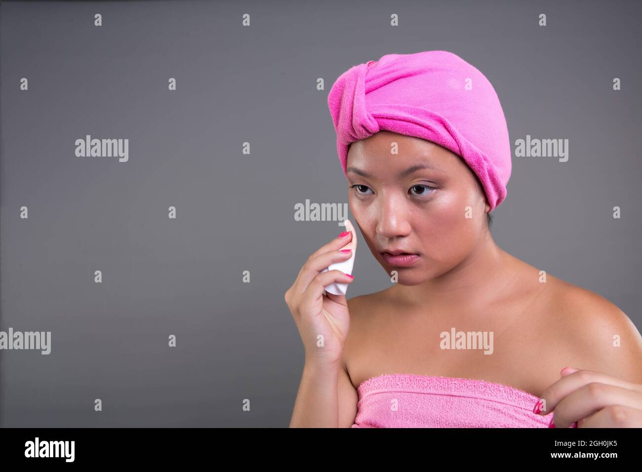 graziosa donna cinese che si prende cura della sua pelle isolata dallo sfondo, concetto di bellezza Foto Stock