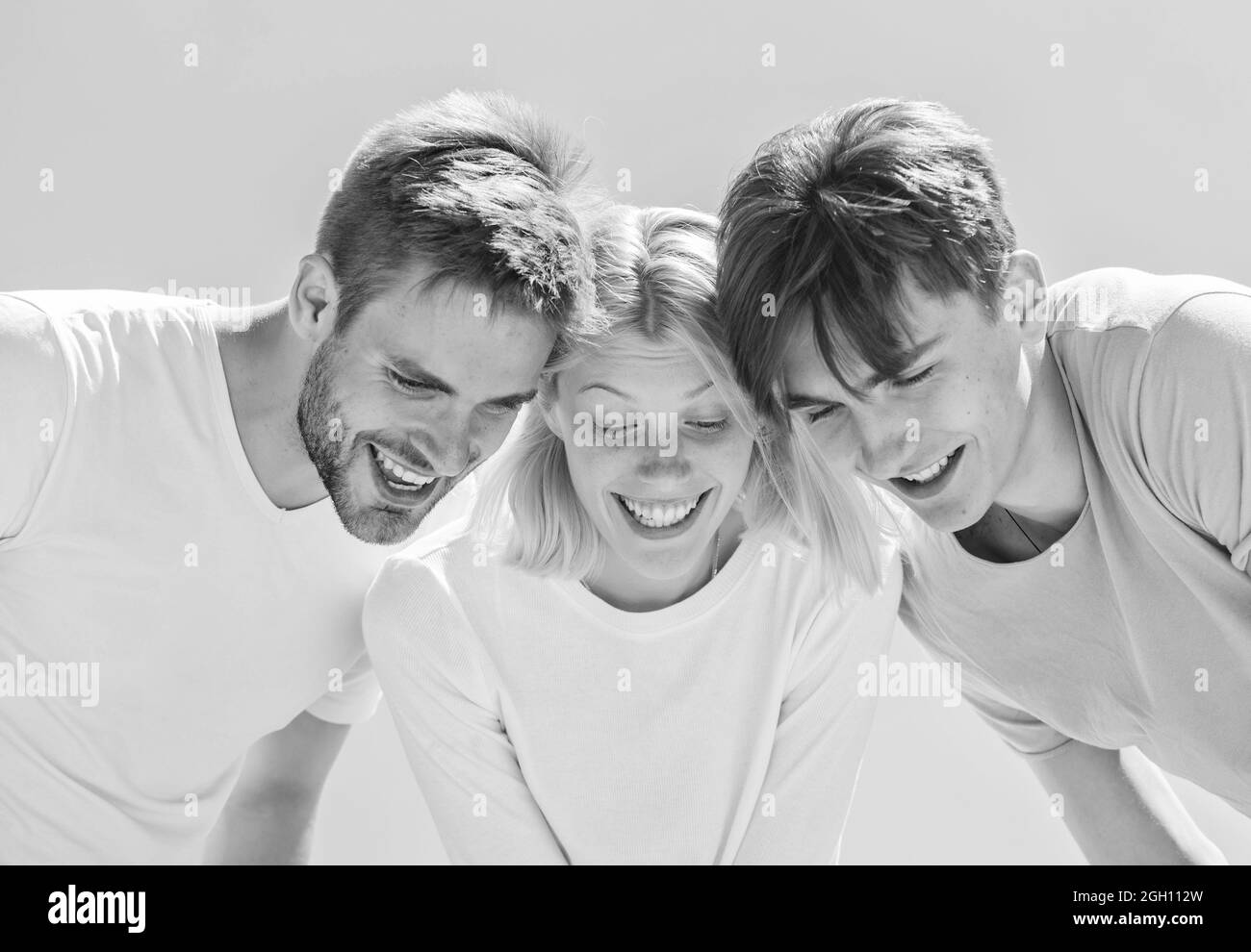 Guarda qui. I giovani spensierati si aggrappano insieme. Vedi qualcosa di adorabile. Felicità. Gruppo persone entusiasta guardare giù. Donna e uomini cielo felice sfondo Foto Stock