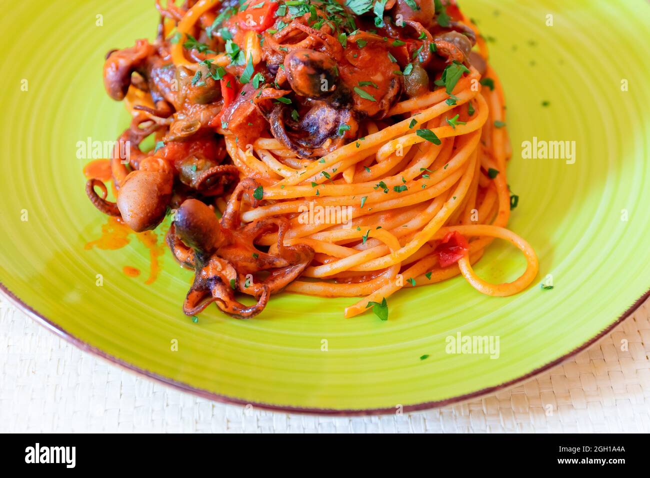 Spaghetti al polpo, salsa di pomodoro, olive e capperi. Ricetta tipica della cucina napoletana, in Italia. Pronto a mangiare. Foto Stock