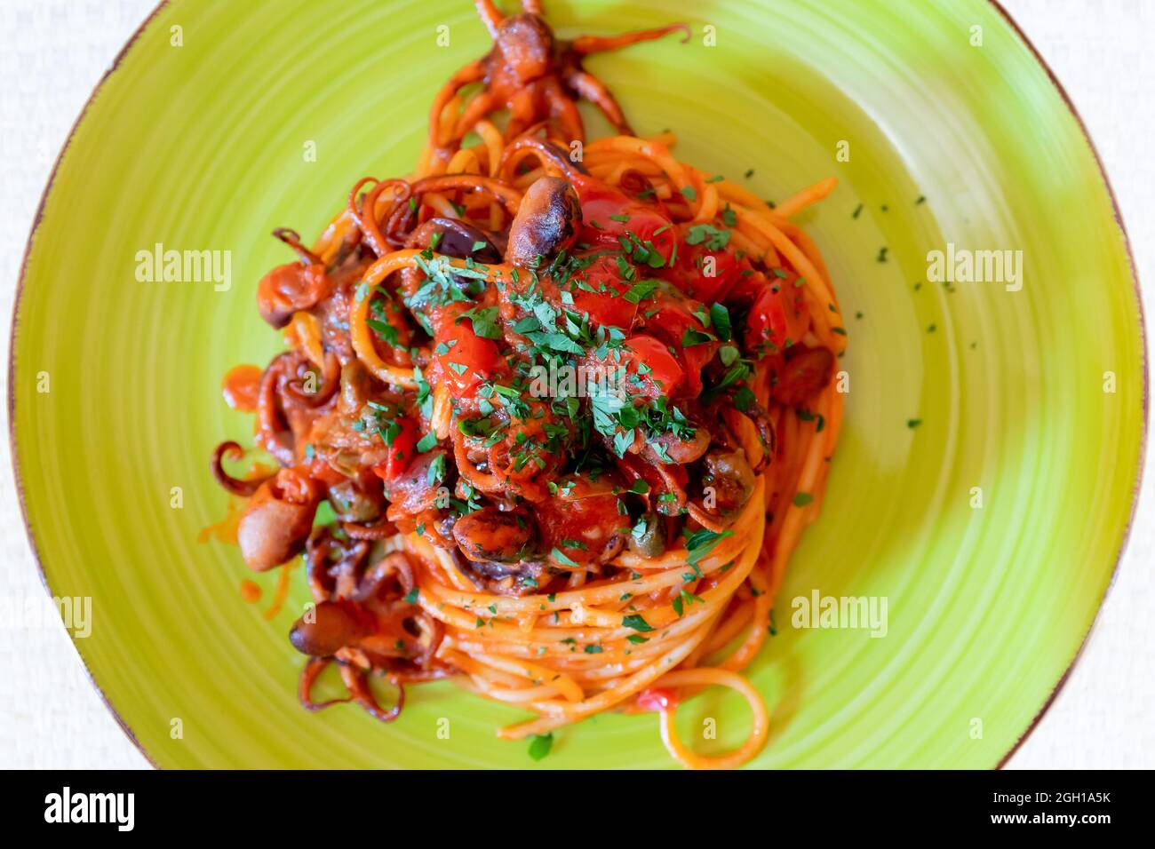 Spaghetti al polpo, salsa di pomodoro, olive e capperi. Ricetta tipica della cucina napoletana, in Italia. Pronto a mangiare. Foto Stock
