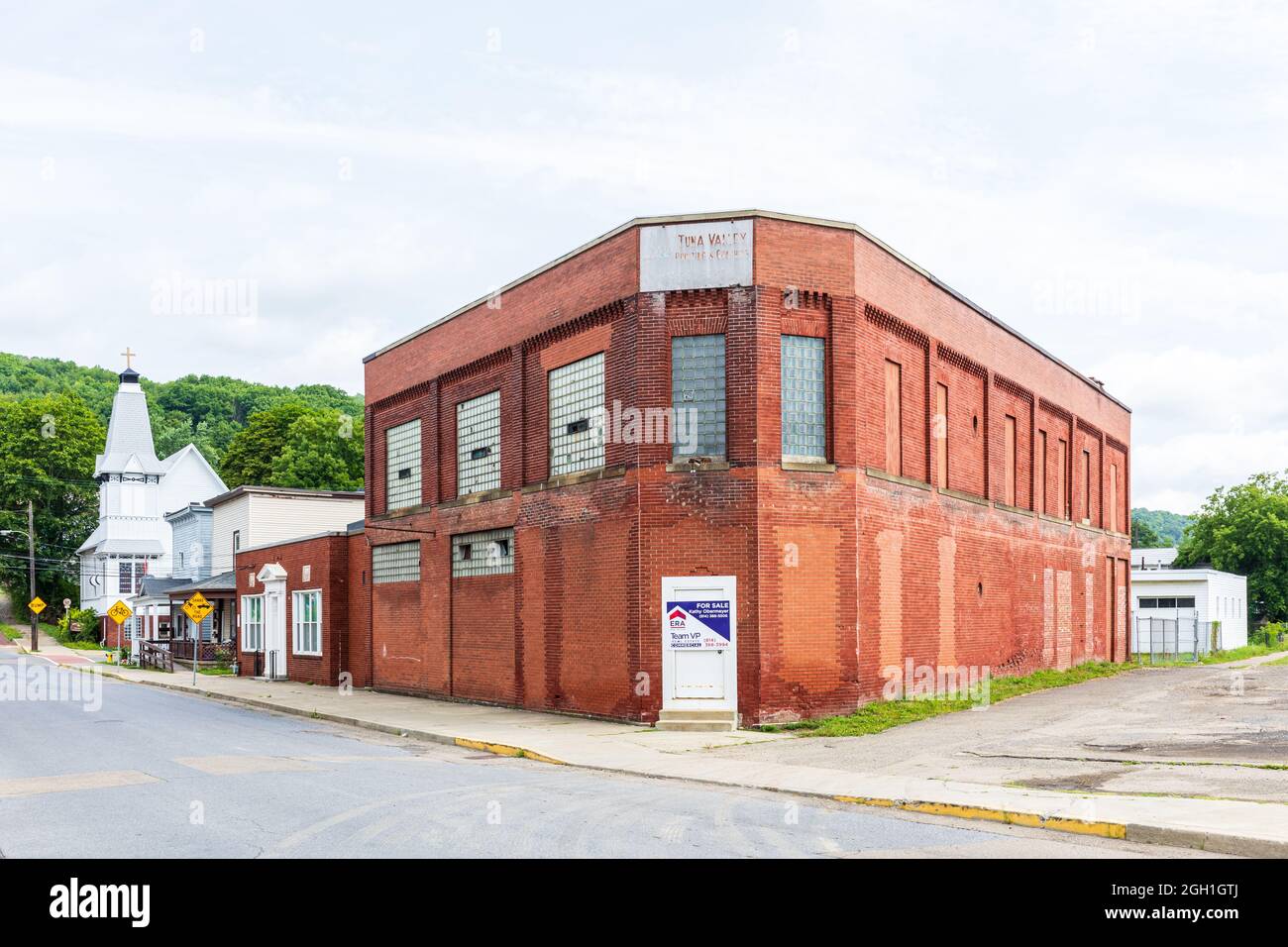 BRADFORD, PA, USA-13 AGOSTO 2021: Un vecchio edificio industriale in mattoni rossi con un cartello sbiadito per Tuna Valley Printing and Graphics sul tetto. Offerta per Foto Stock
