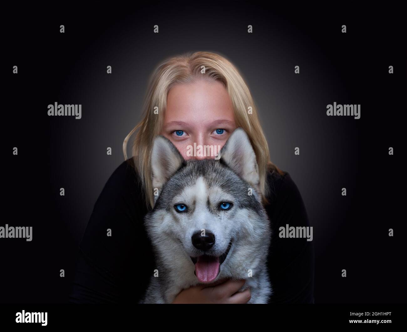 Ritratto di una ragazza e di un cane con occhi blu su sfondo scuro Foto Stock