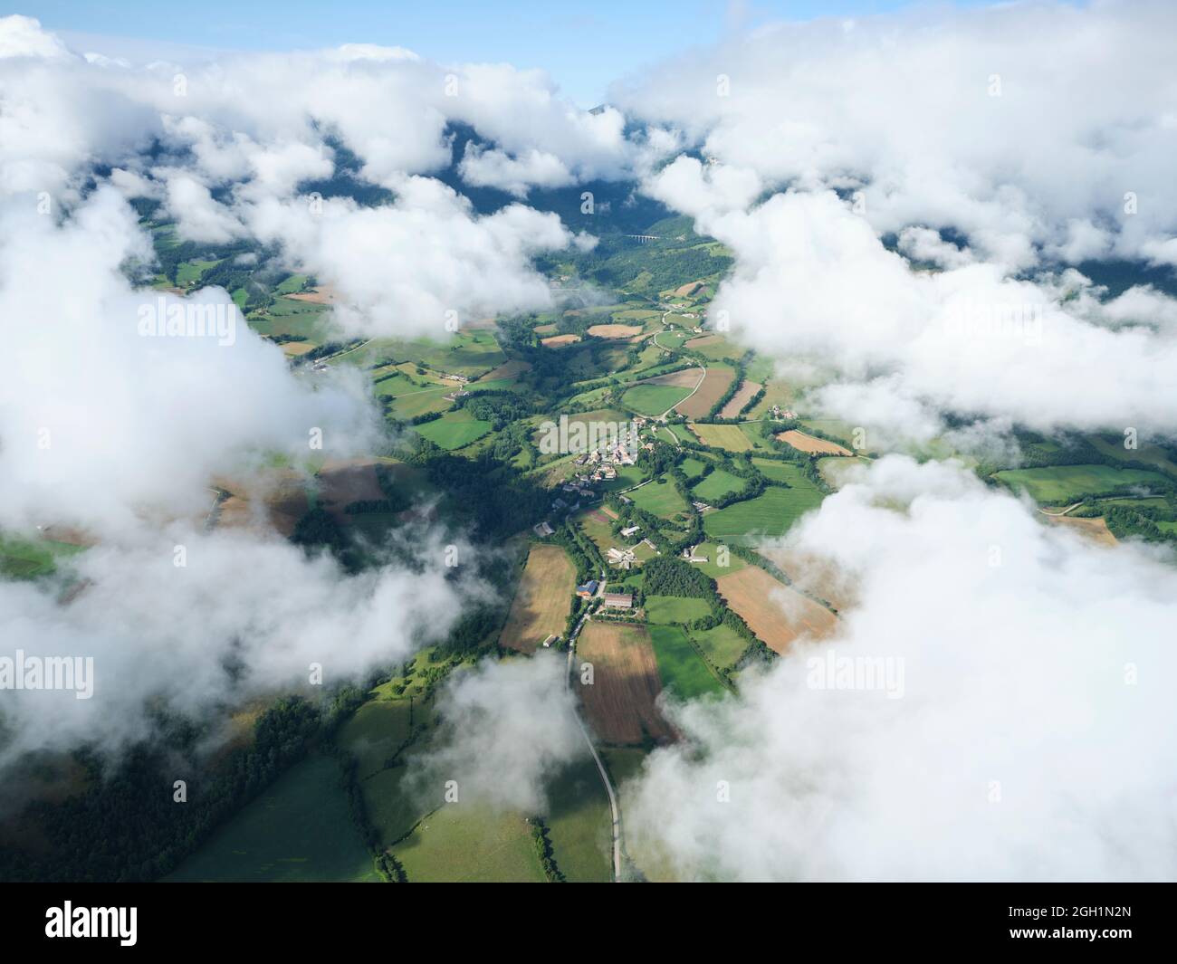 VISTA AEREA. Villaggio di Percy circondato da nuvole a bassa quota al mattino. Regione di Trièves, Isère, Francia. Foto Stock