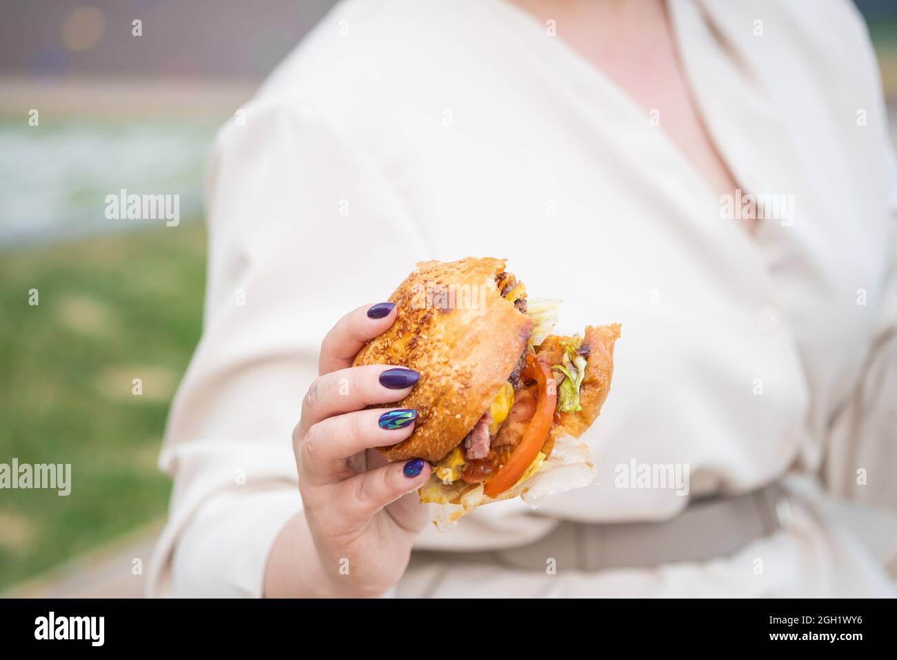 Primo piano di una donna che mangia un hamburger. Cattive abitudini alimentari Foto Stock