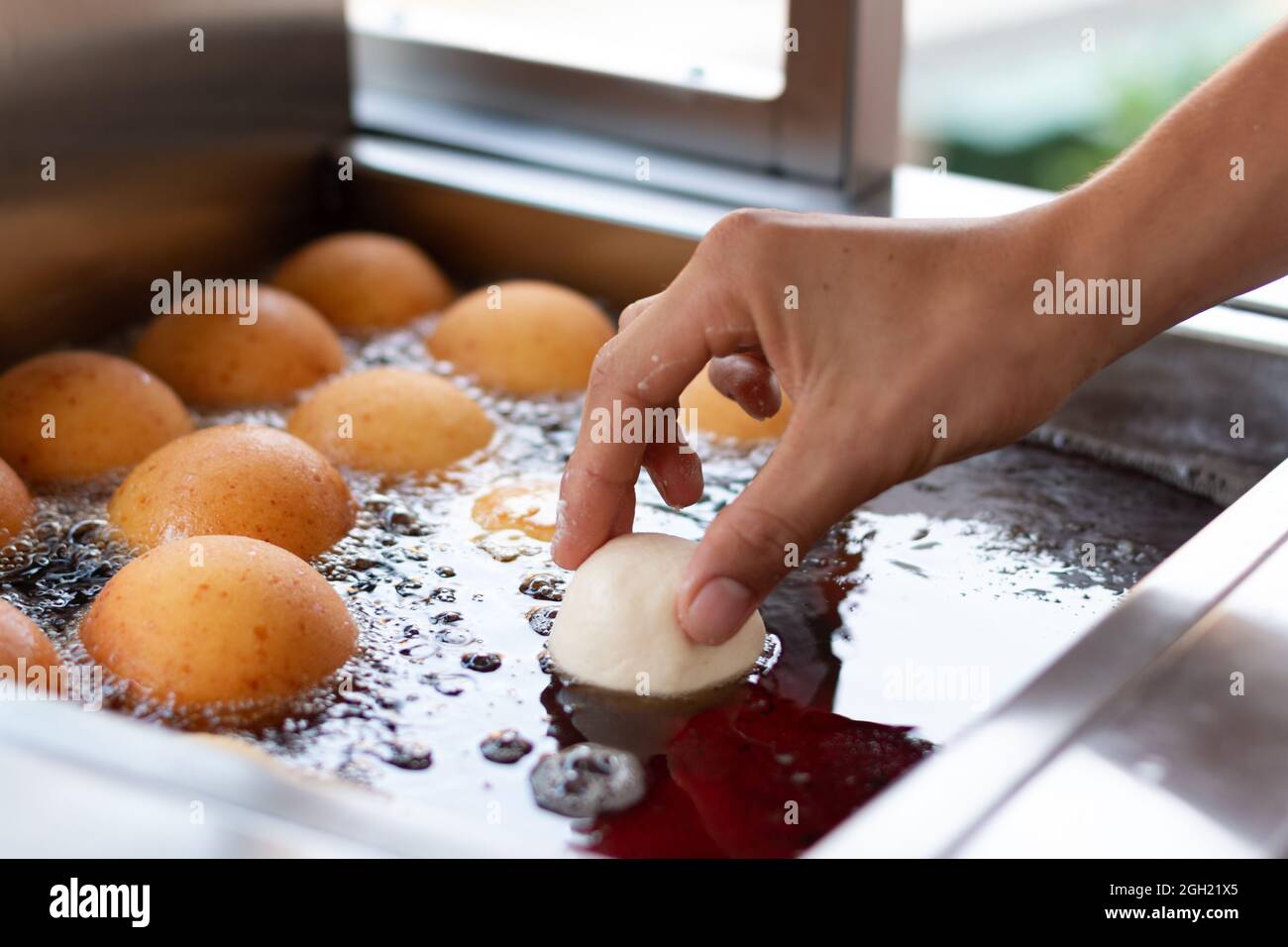 Mano che cade ciambella in oil.Preparing cibo latino tradizionale per natale. Foto Stock