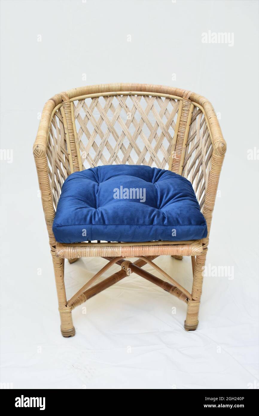Sedia in canna di rattan con cuscini blu sfondo bianco morbido fuoco Foto Stock