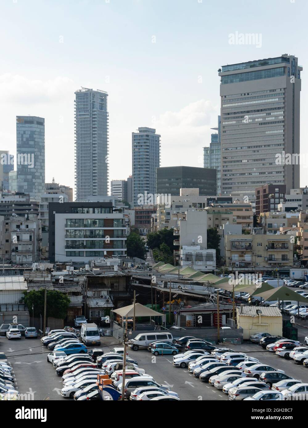 Un paesaggio urbano del sud di Tel Aviv, Israele, tra cui alti riser oltre a vecchi edifici più piccoli, un mercato e un parcheggio. Foto Stock