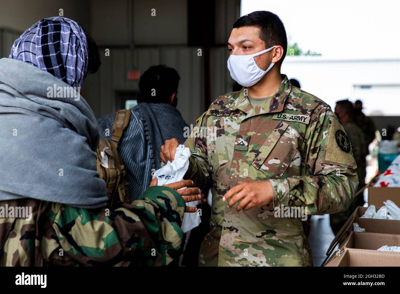 Esercito degli Stati Uniti Pvt. Adam Sandoval, attaccato al 720th Military Police Battaglione, 89th Military Police Brigade dispiegato da Fort Hood, Texas, consegna una borsa di cura della Croce Rossa ad un evacuatore afghano durante il processo di ricezione a Fort McCoy, Wisconsin, 3 settembre 2021. Molte famiglie afghane sono arrivate negli Stati Uniti con pochi beni. Il Dipartimento della Difesa, attraverso il comando del Nord degli Stati Uniti, e in supporto del Dipartimento della sicurezza interna, sta fornendo trasporto, alloggio temporaneo, screening medico, e supporto generale per almeno 50,000 evacuati afghani in strutture adeguate, in Foto Stock