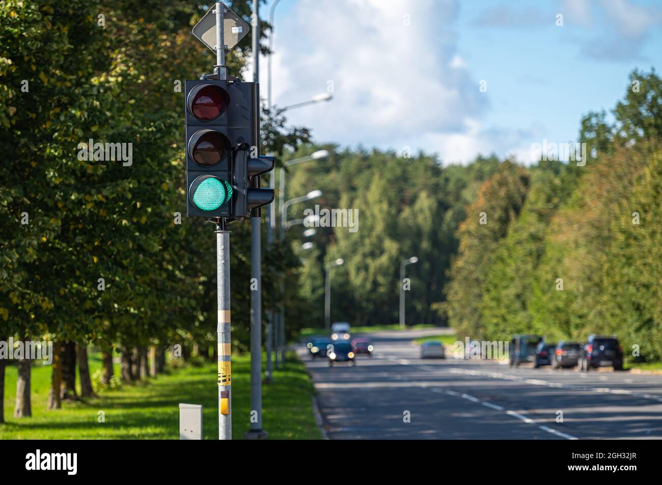 primo piano del semaforo con semaforo verde sulla strada della città defocused Foto Stock