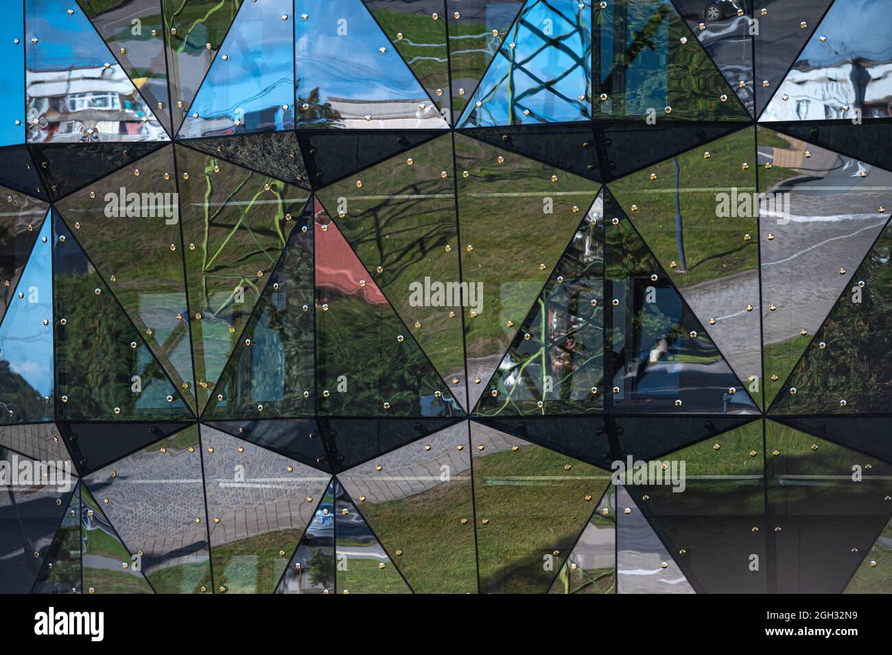 primo piano della facciata rivestita di vetro di un moderno edificio coperto da triangoli riflettenti di vetro Foto Stock