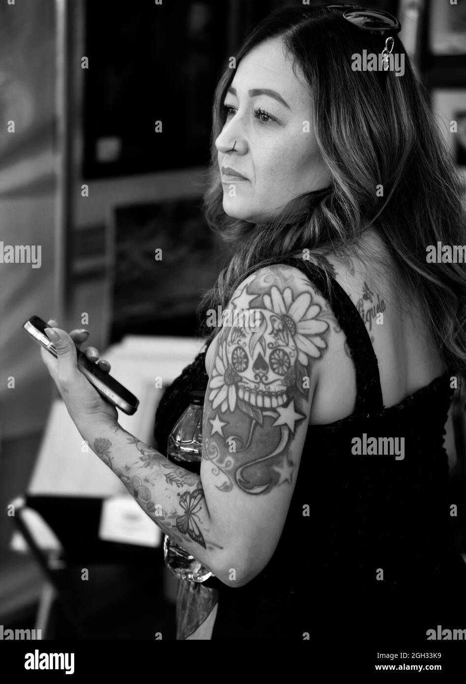 Una donna con tatuaggi sul braccio utilizza il suo smartphone durante la visita a Santa Fe, New Mexico. Foto Stock