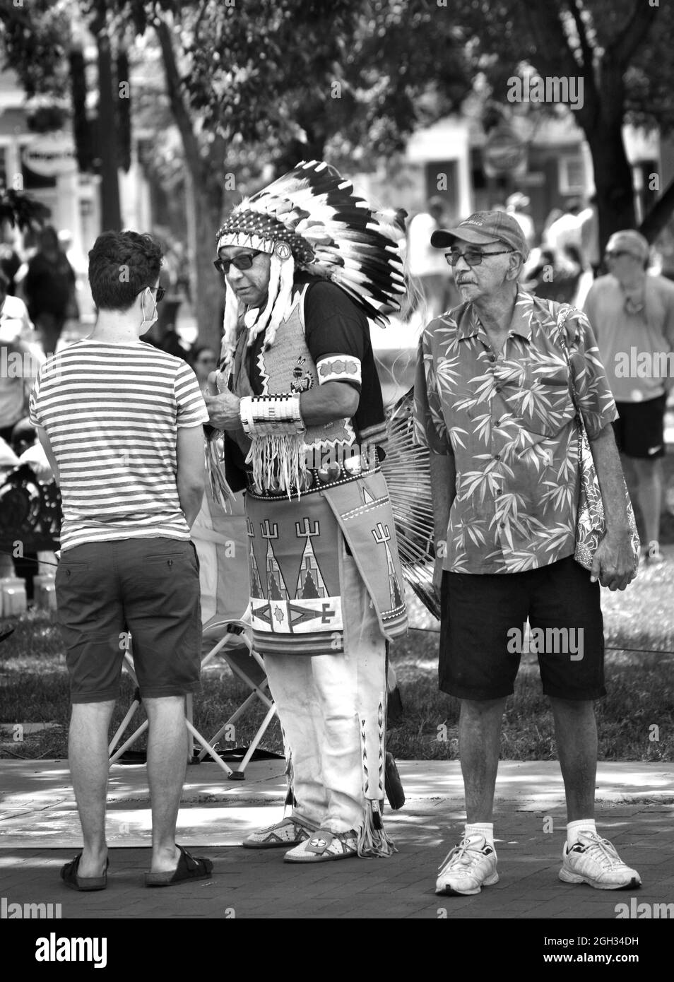 Un uomo nativo americano vestito in pieno Plains Indians regalia parla con i turisti in visita a Santa Fe, New Mexico. Foto Stock