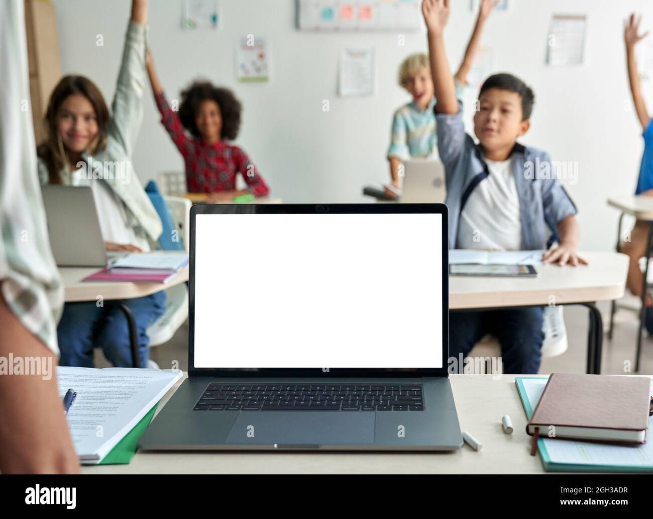 Computer portatile bianco vuoto schermo vuoto mockup sul tavolo degli insegnanti in classe. Foto Stock