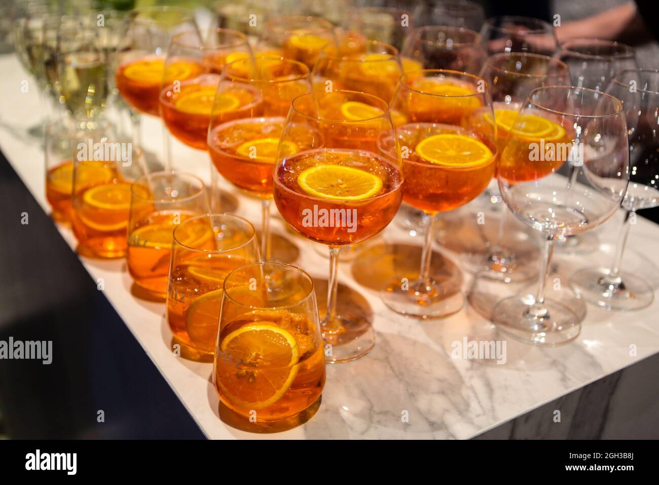 Molti bicchieri con un cocktail alcolico a base di Aperol sul tavolo del buffet. Cocktail alcolico Aperol Spritz. Cocktail alcolici al bar Foto Stock