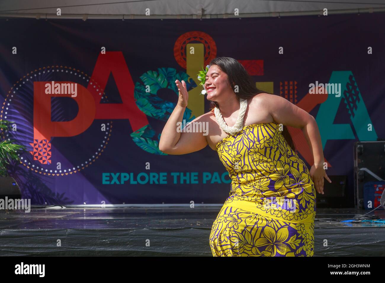 Una donna polinesiana che balla davanti al logo del Festival Pasifika, una celebrazione annuale della cultura dell'isola del Pacifico ad Auckland, Nuova Zelanda Foto Stock