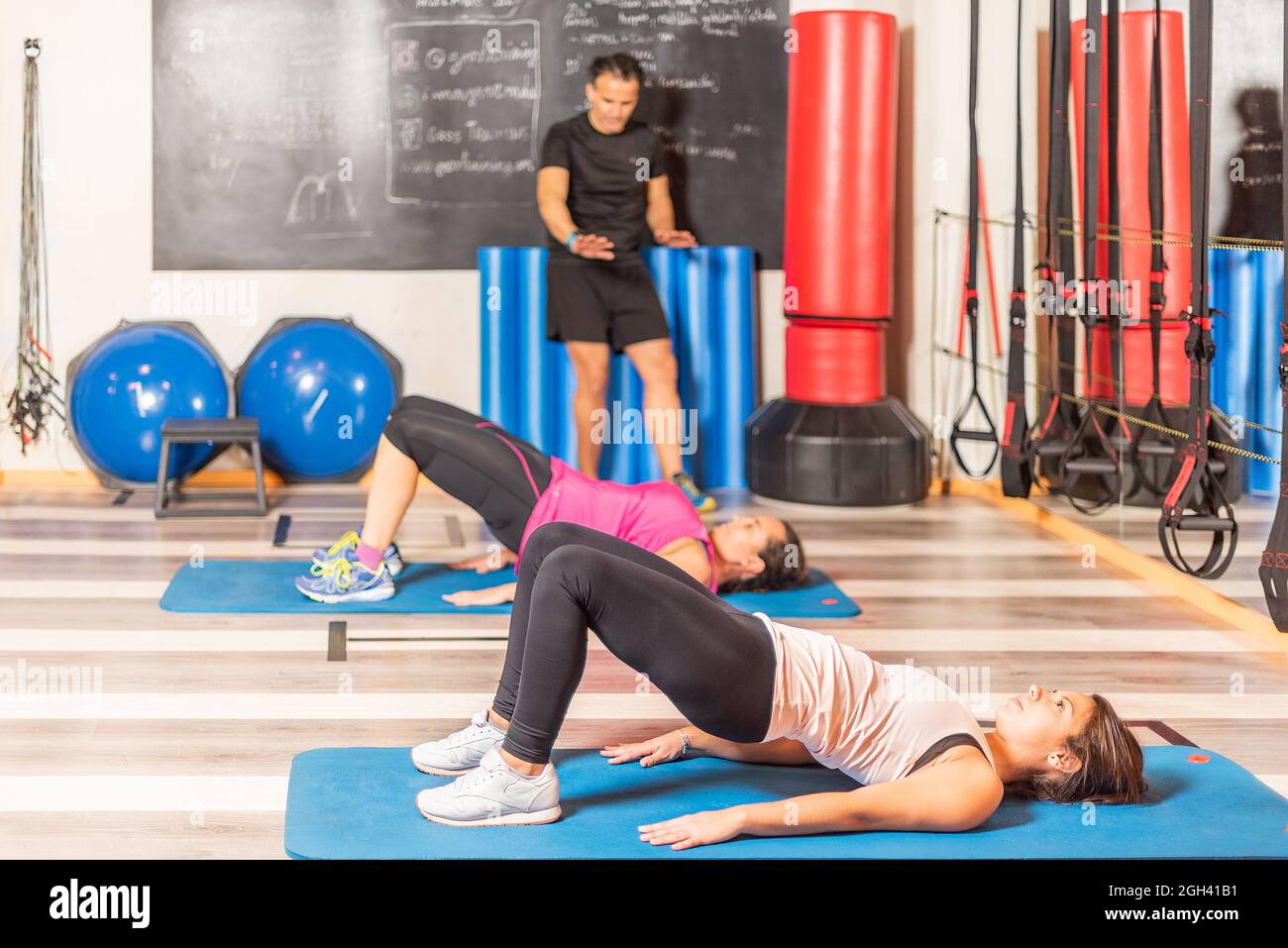 Donne che fanno esercizio pelvico con allenatore in palestra Foto Stock