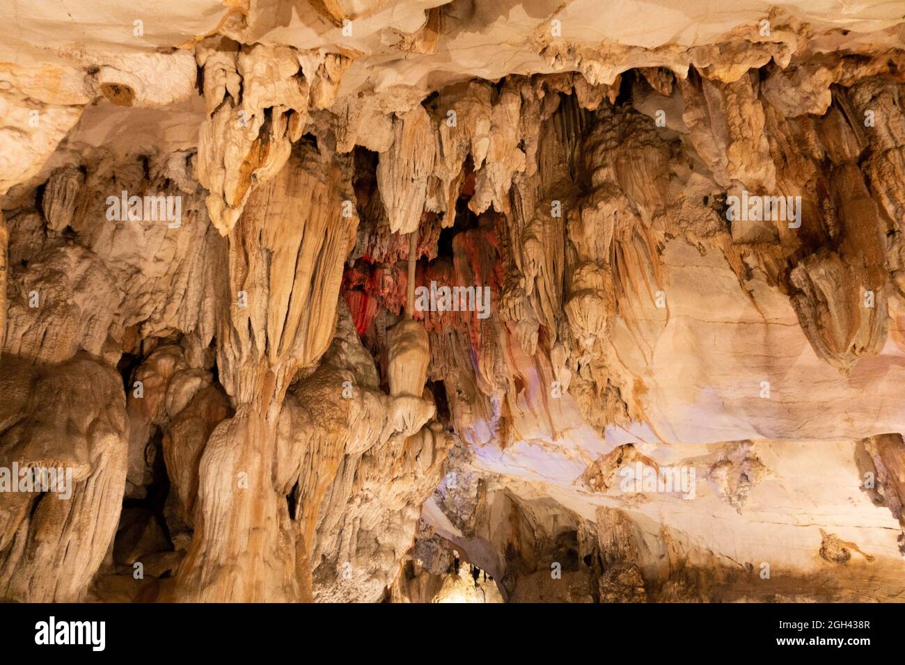 Stalattite, formazione minerale, è appesa al soffitto della grotta, la maggior parte di colore arancione chiaro. Foto Stock