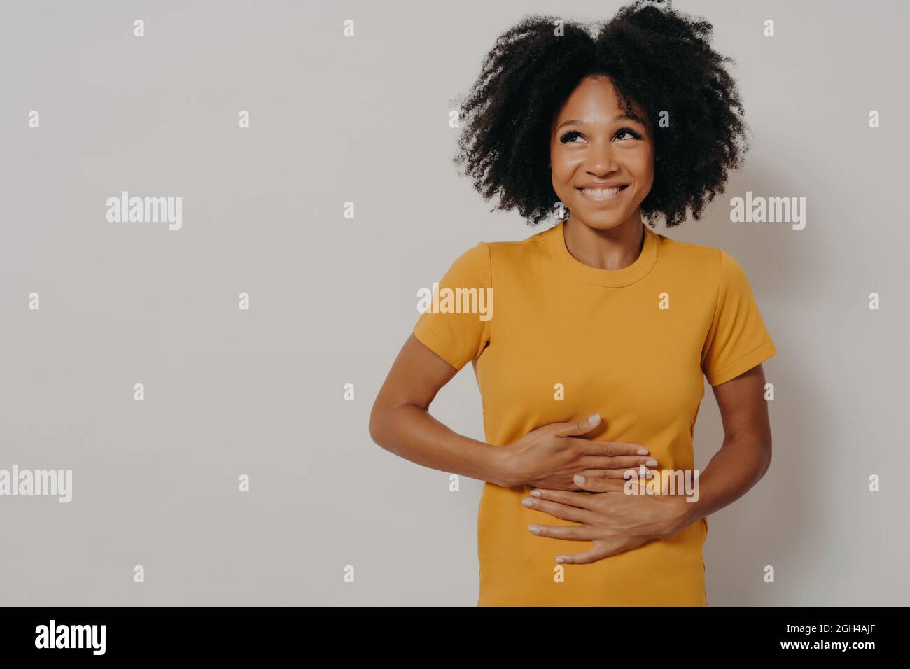Felice afroamericana donna ridendo fuori forte ad un certo scherzo esilarante, mantenendo le mani sullo stomaco Foto Stock