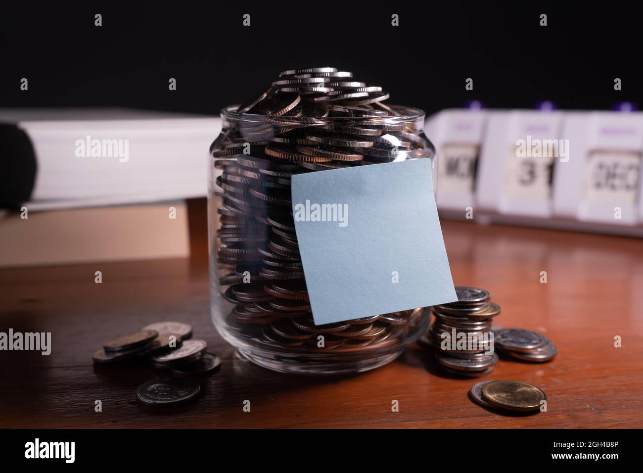 Risparmi alla fine dell'anno. Un vaso pieno di monete con blocco memoria vuoto per il testo. Foto Stock