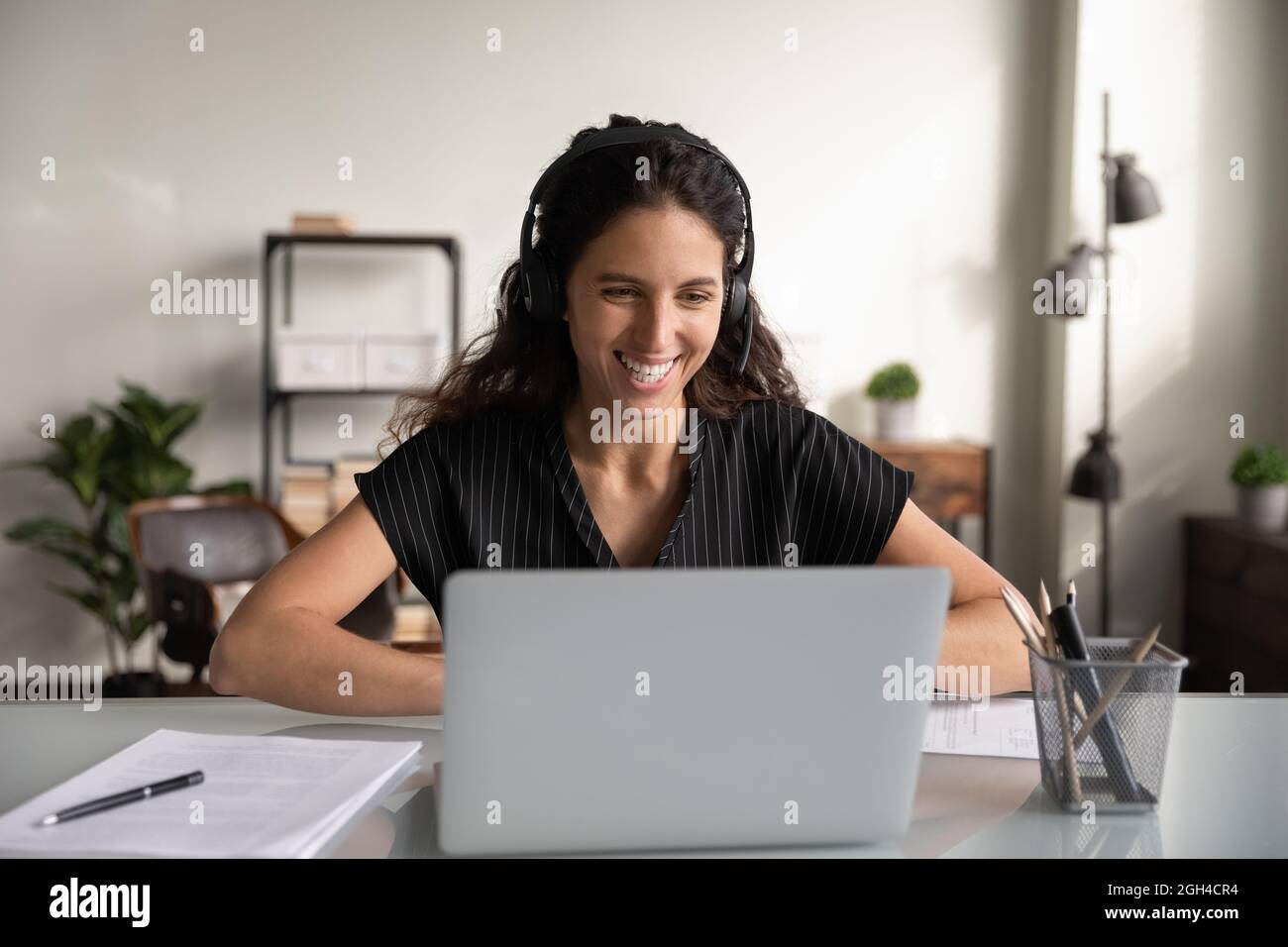 Felice donna d'affari millenaria in cuffia, che lavora al notebook Foto Stock