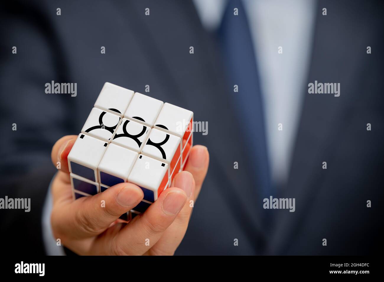 Le mani di un uomo d'affari che tiene un cubo con un'icona della gente visibile. Foto Stock Le mani di un uomo d'affari che tiene un cubo con un'icona della gente visibile. Foto Stock
