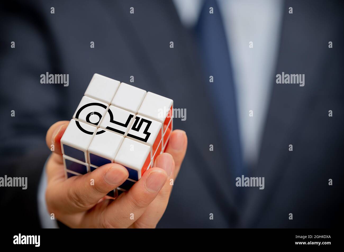 Mani di un uomo d'affari che tiene un cubo con un'icona chiave visibile. Foto Stock Mani di un uomo d'affari che tiene un cubo con un'icona chiave visibile. Foto Stock