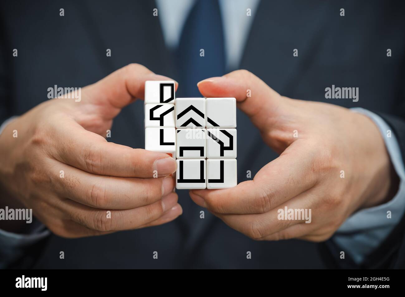 La mano di un uomo d'affari che tiene un cubo con una vista dell'icona della casa. Foto Stock La mano di un uomo d'affari che tiene un cubo con una vista dell'icona della casa. Foto Stock