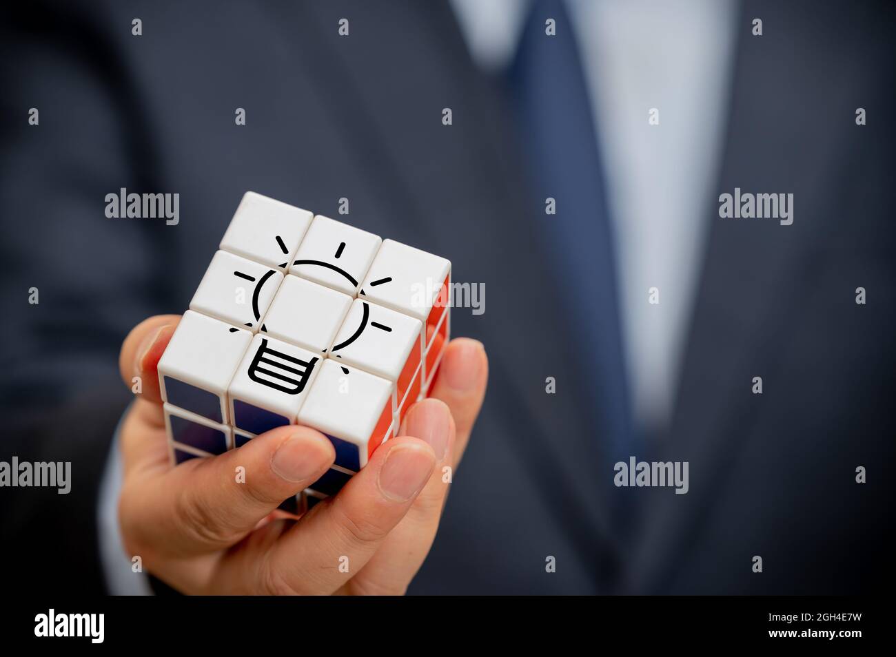La mano di un uomo d'affari che tiene un cubo con una vista dell'icona della lampadina. Foto Stock La mano di un uomo d'affari che tiene un cubo con una vista dell'icona della lampadina. Foto Stock