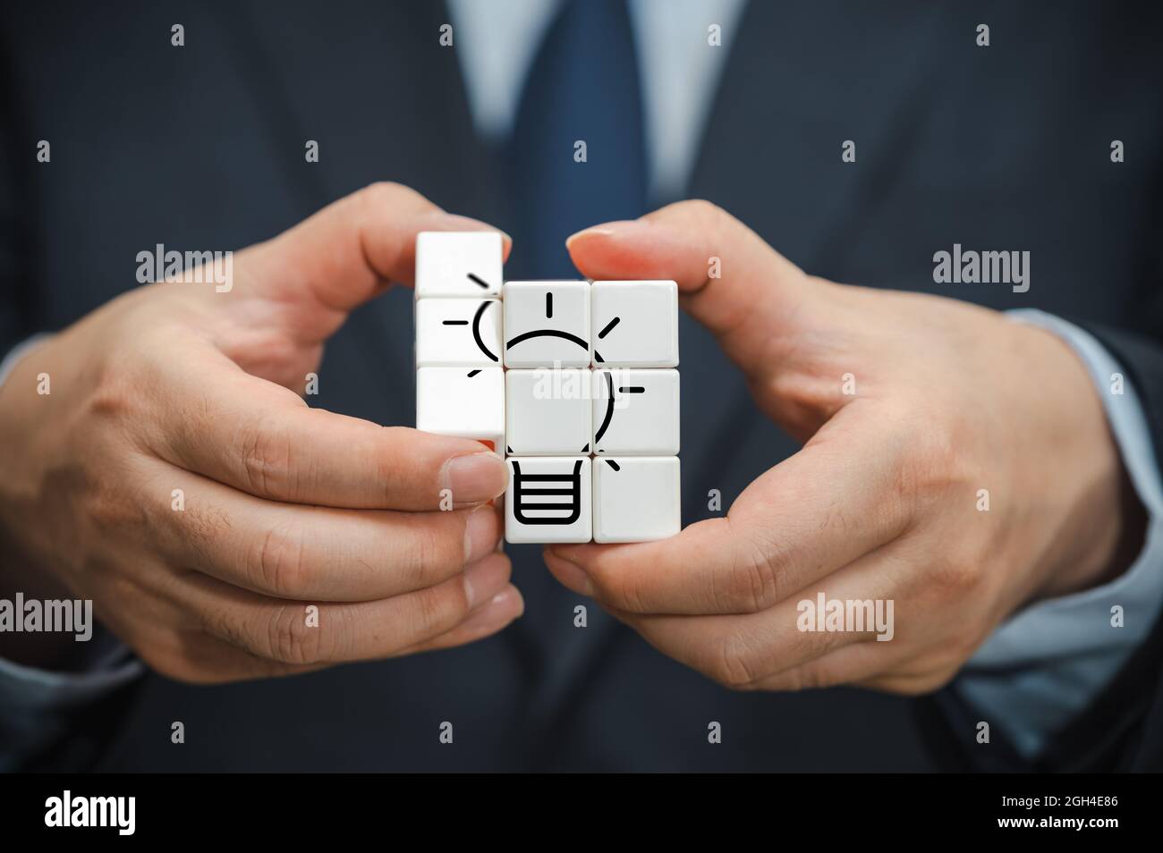 La mano di un uomo d'affari che tiene un cubo con una vista dell'icona della lampadina. Foto Stock La mano di un uomo d'affari che tiene un cubo con una vista dell'icona della lampadina. Foto Stock