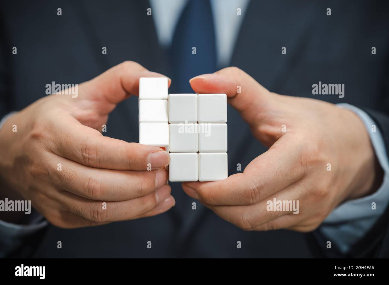 La mano di un uomo d'affari che tiene un cubo con una vista del lato bianco. Foto Stock La mano di un uomo d'affari che tiene un cubo con una vista del lato bianco. Foto Stock