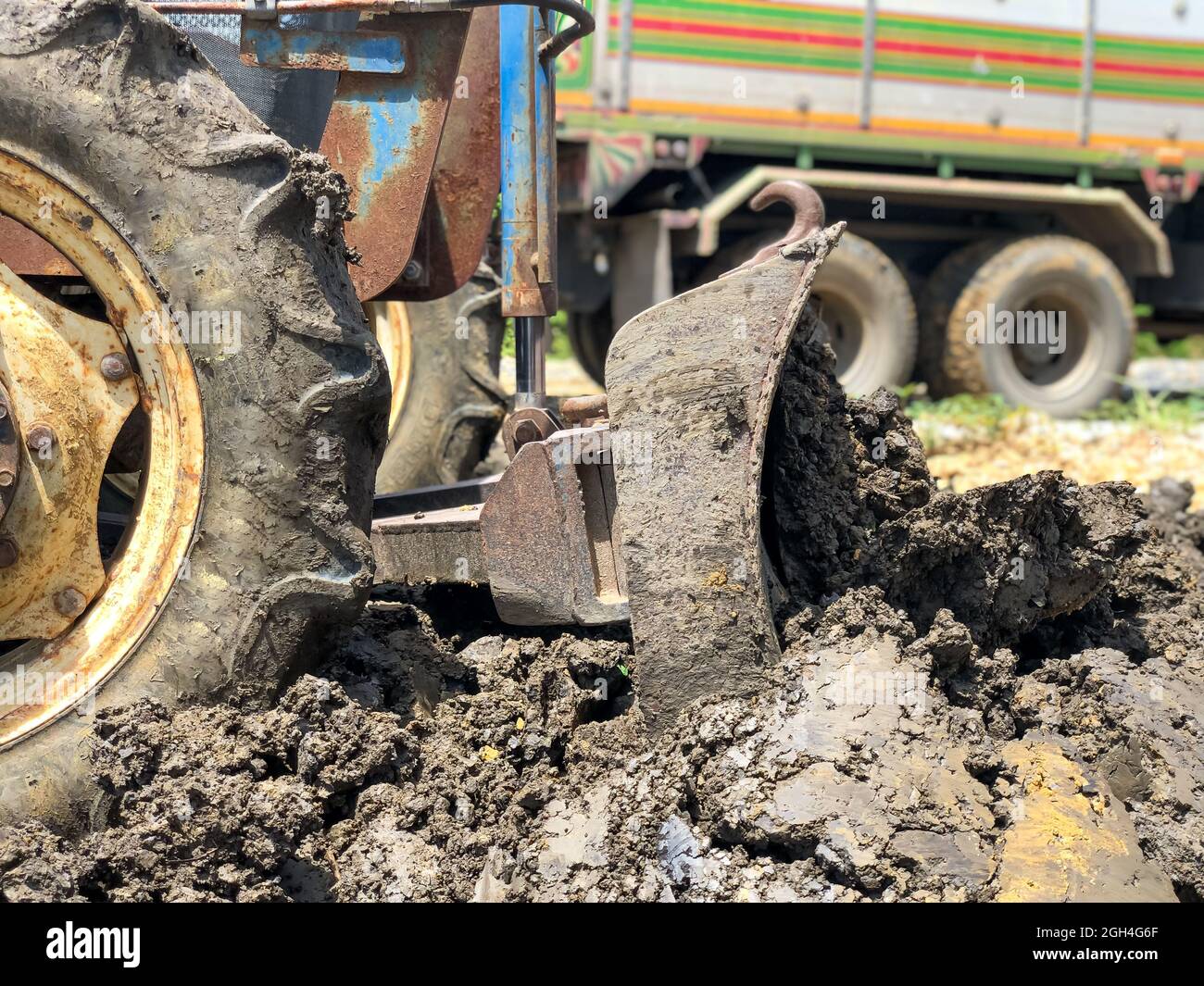 Il trattore sta regolando il terreno. Dumper in background Foto Stock