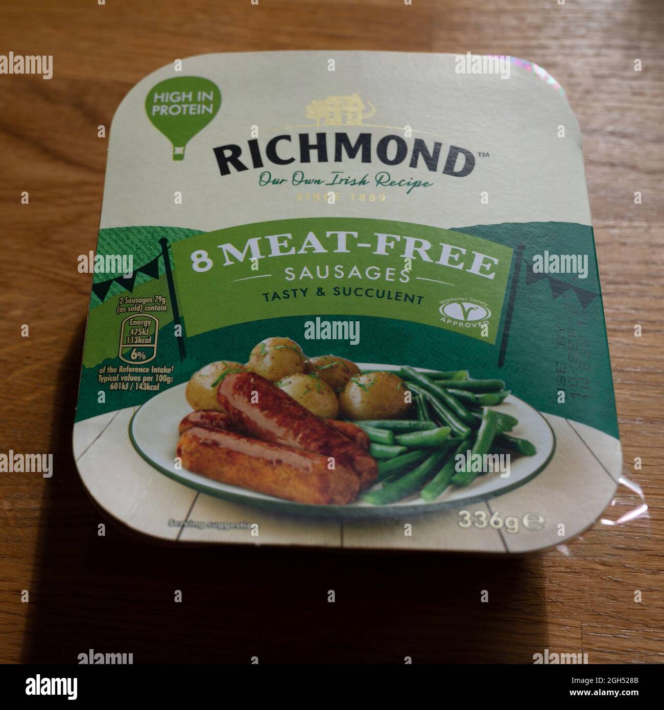 Editoriale illustrativo di pacchetto di salsicce vegane senza carne di Richmond in imballaggio. Sul piano di lavoro della cucina in legno. Foto Stock