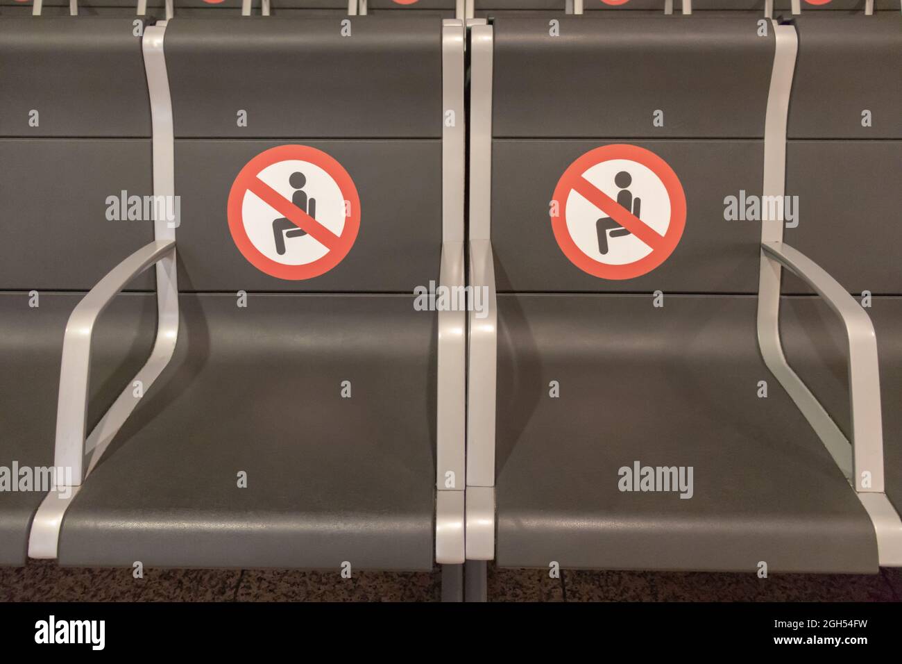 BARCELLONA, SPAGNA - AGOSTO 18,2021: Due posti a sedere nell'aeroporto di Barcellona terminal di partenza senza seduta e tenere i cartelli di distanza Foto Stock