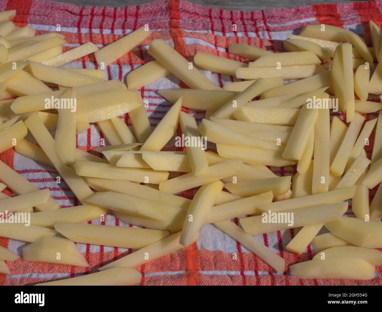 È sufficiente tagliare e lavare le patatine fritte belghe su un asciugamano bianco rosso Foto Stock