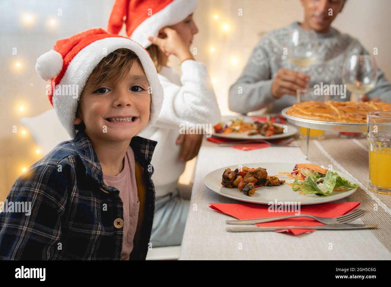La famiglia felice festeggia il Natale insieme a una cena vegana al coperto a casa - Focus on boy face Foto Stock
