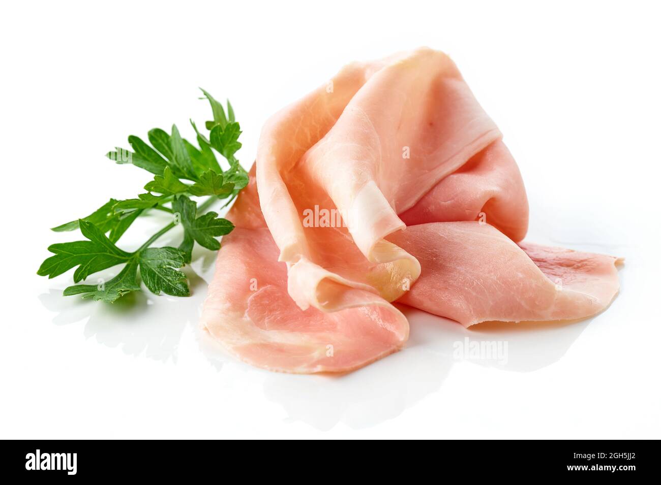 Fette di prosciutto e foglia di prezzemolo isolate su fondo bianco Foto Stock