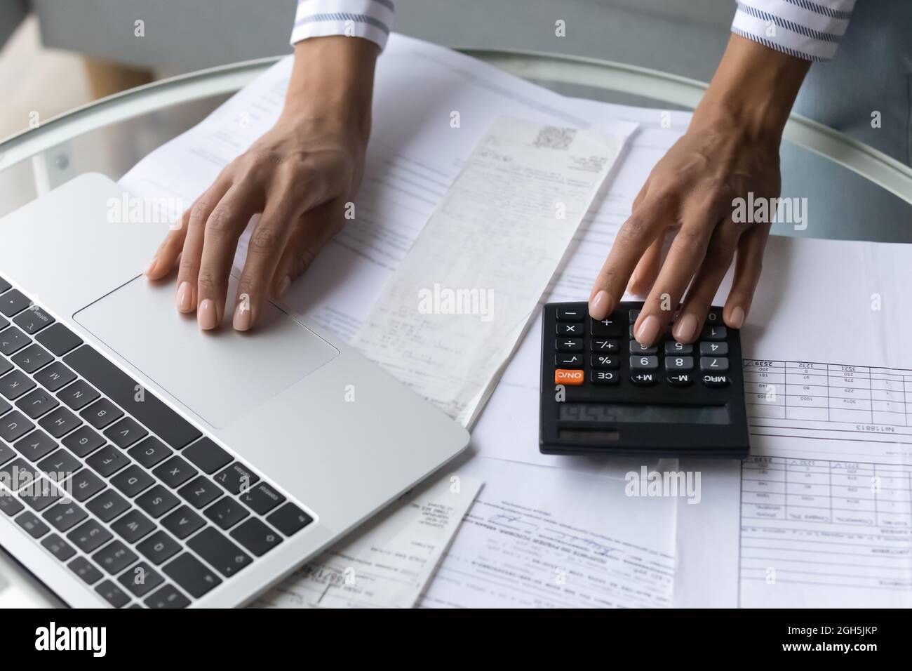 Mani nere femminili che utilizzano la calcolatrice e il computer portatile a casa Foto Stock