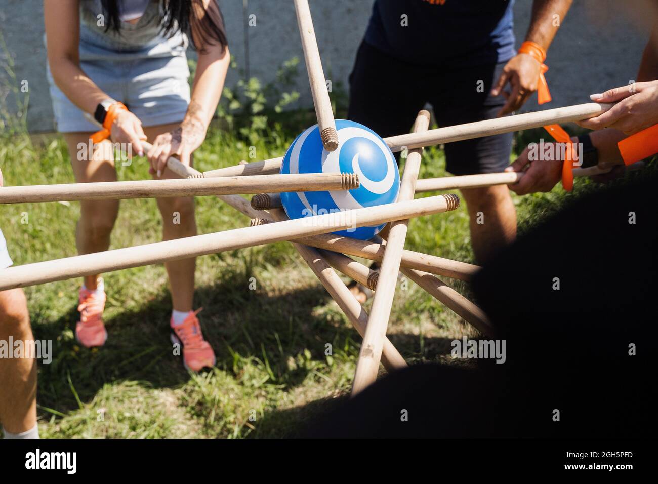 Gioco di teambuilding per gruppi di persone per ottenere lo spirito di squadra e aumentare l'amicizia per i colleghi. Gioco di squadra con palla e bastoni. Foto Stock