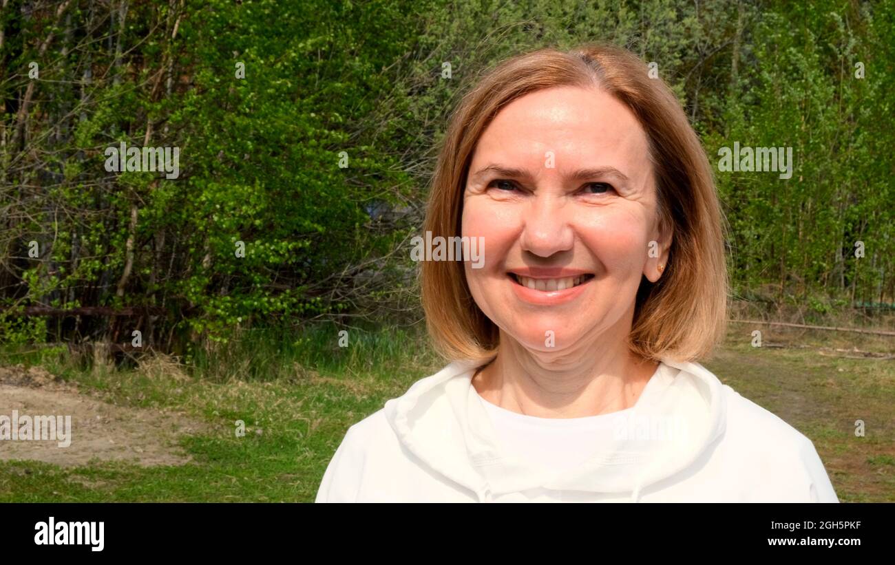 Bella donna matura faccia. Donna mid adult sorridente all'aperto. Ritratto di femmina 55-60 anni rilassante in giardino. Foto Stock