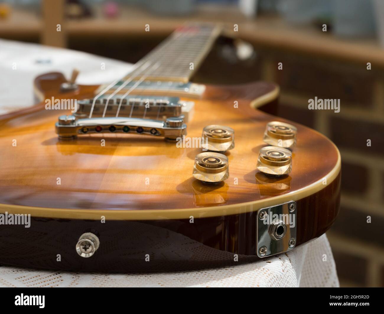 Una vista da primo piano di una chitarra elettrica retrò che mostra le manopole di controllo del tono e del volume e il jack point.Blurred sullo sfondo è il ponte e il collo con strin Foto Stock