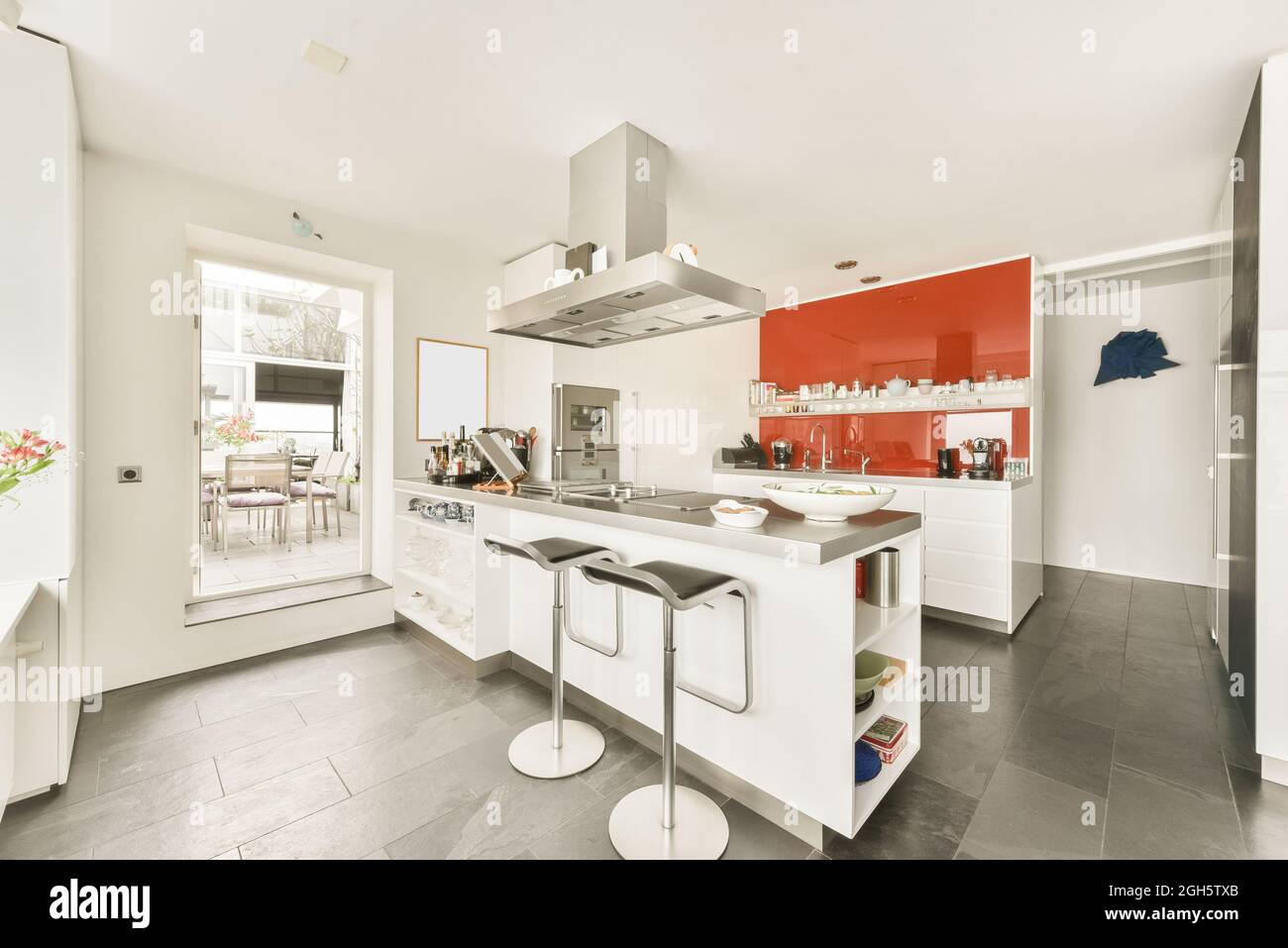 Cucina isola con bancone e sgabelli bar sotto il cofano in moderno  appartamento open space con pareti bianche con mobili e utensili Foto stock  - Alamy