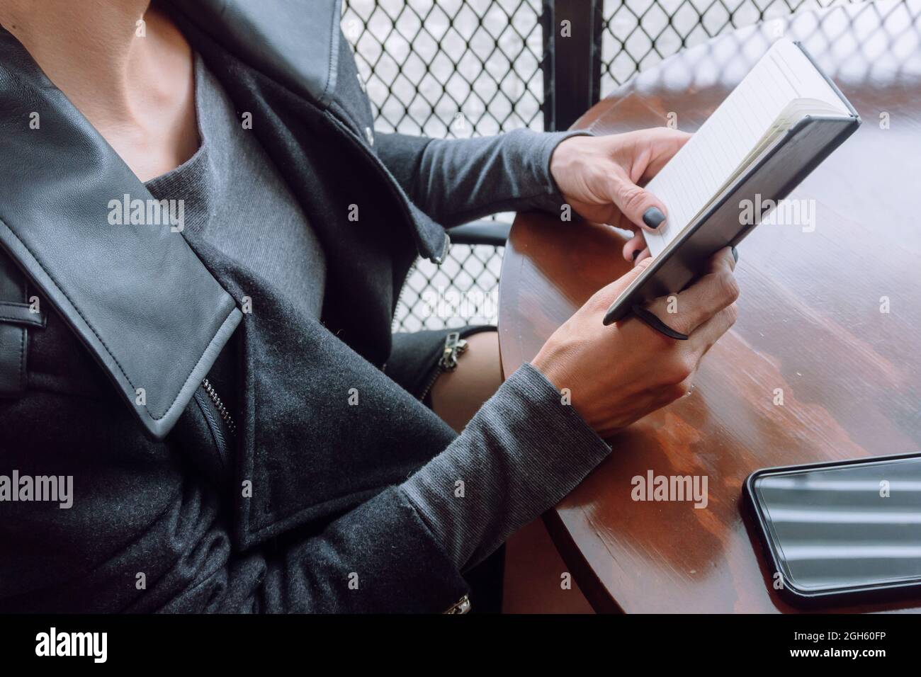 Da sopra di raccolto anonima femmina in abiti casual tenendo aperto notebook su tavola di legno Foto Stock