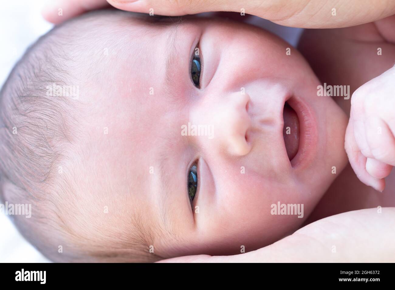 Primo piano di raccolto anonima madre toccare testa di bambino carino sorridente e guardando la macchina fotografica Foto Stock